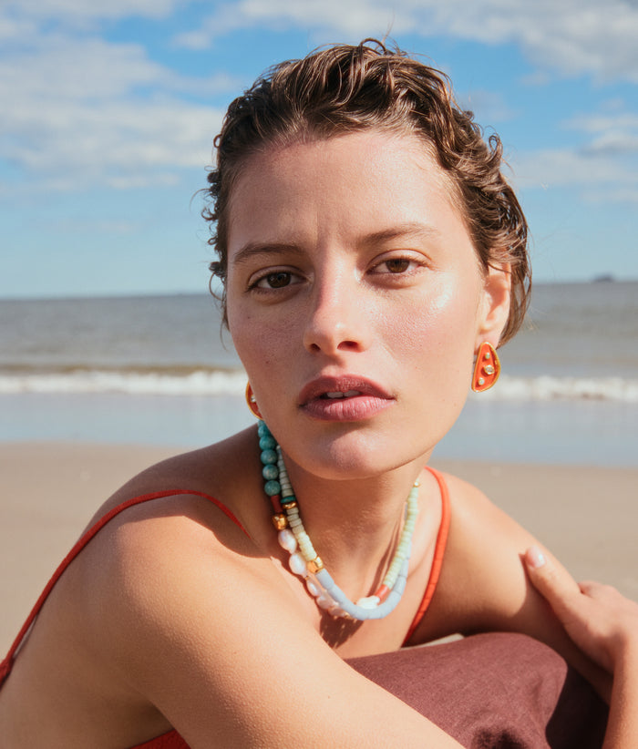 Model on beach wears Isola Studs and Cabana Necklace in Isla