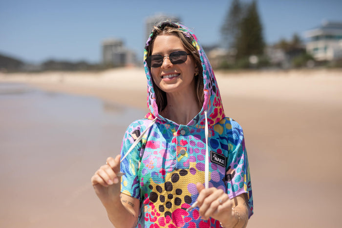 Kasey Rainbow hooded towel in multicolour geometric pattern with hood up, worn at beach