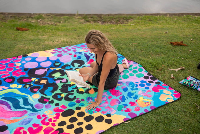 Kasey Rainbow recycled picnic blanket with multicoloured geometric and polka dot pattern spread on grass