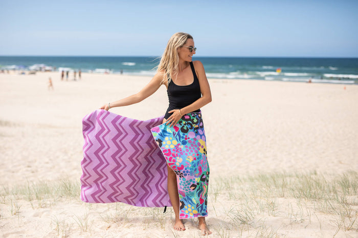 Purple chevron and multicolored patterned recycled sand-free beach towel held on beach