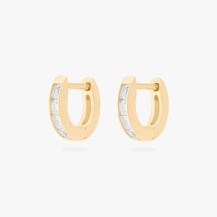 This is an image of a pair of 14K gold plated huggie earrings with 4 baguette cut, bezel set crystal CZs along the edge.