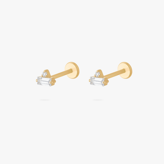 Pair of gold flatback earrings with small clear and baguette stones on a white background