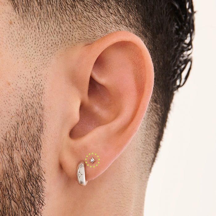 This is an image of a silver-toned flatback stud that is in the shape of a twinkle star with a clear CZ in the middle on ear. [hover] color:null|silver/clear