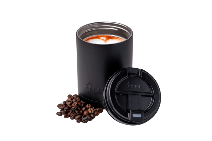 Black insulated coffee cup with latte art, matching black lid, and scattered coffee beans beside it