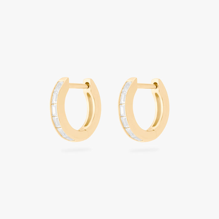 This is an image of a pair of 14K gold plated huggie earrings with 6 baguette cut, bezel set crystal CZs along the edges.