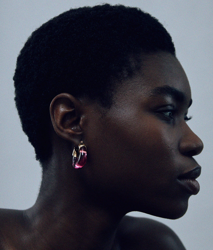 Model on grey background with the Mini Organic Hoops in Flamingo.