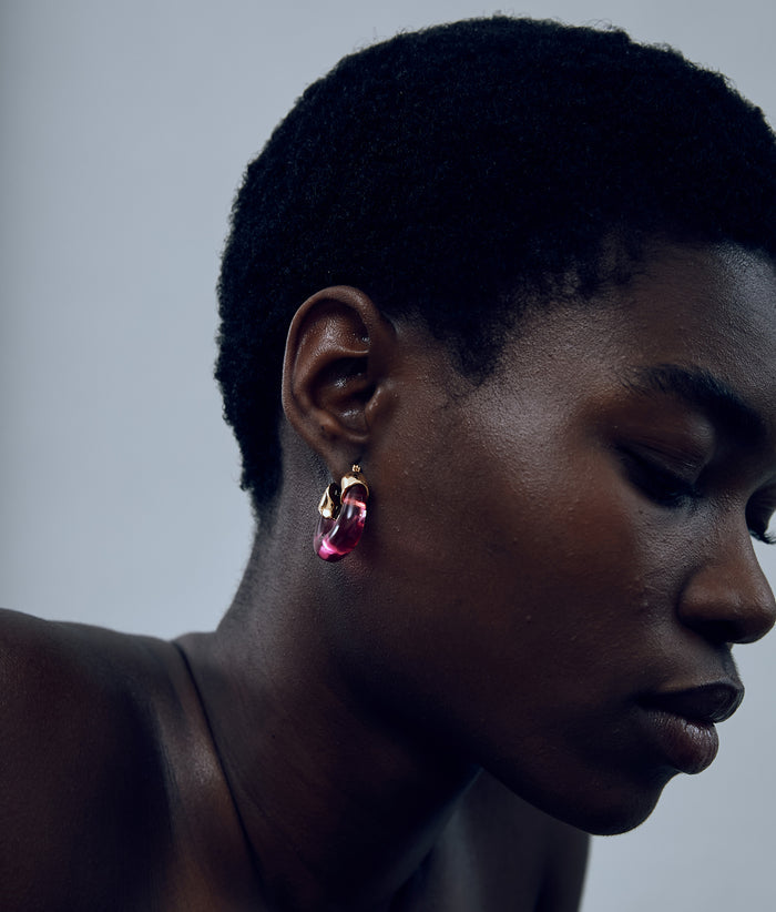 Another angle of model on grey background with the Mini Organic Hoops in Flamingo.