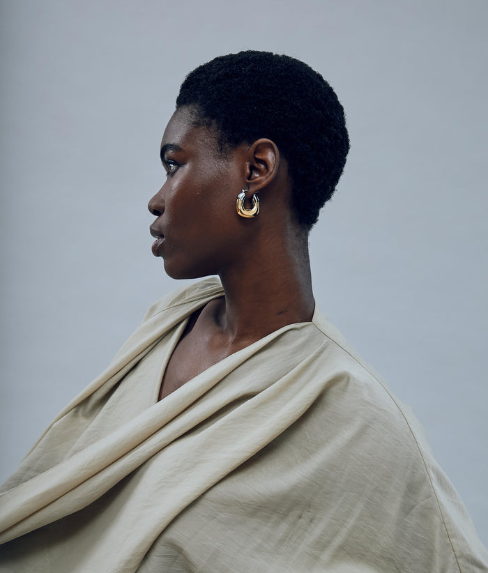 Model on grey background with the Mini Organic Hoops in Mixed Metal.