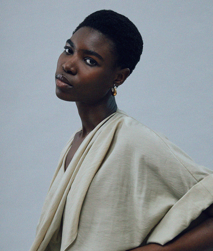 Another angle of model on grey background with the Mini Organic Hoops in Mixed Metal.