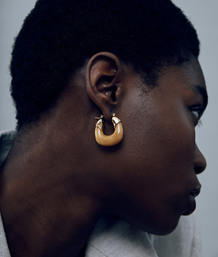 Close-up of model on grey background with the Mini Organic Hoops in Mocha.