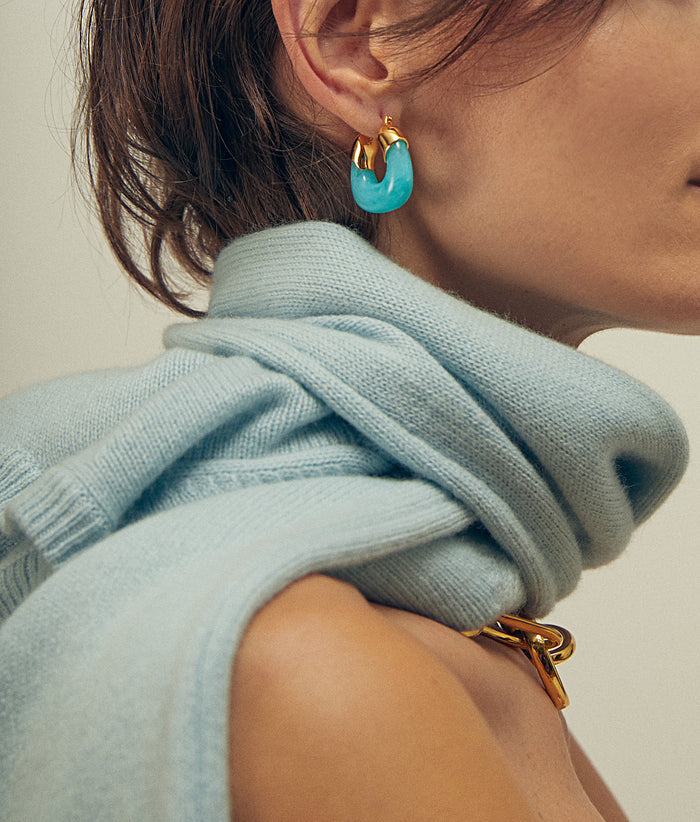 Model in profile wears Mini Organic HOops in Pool with blue sweater tied around her neck