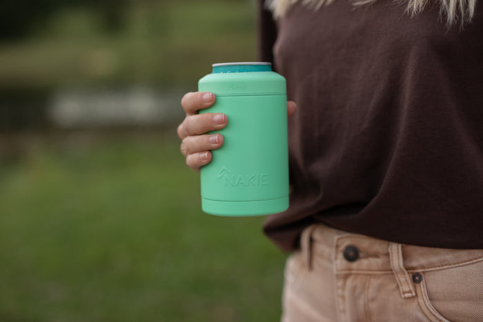 Mint green insulated coffee cup with teal lid held in hand, showing cylindrical design with embossed branding