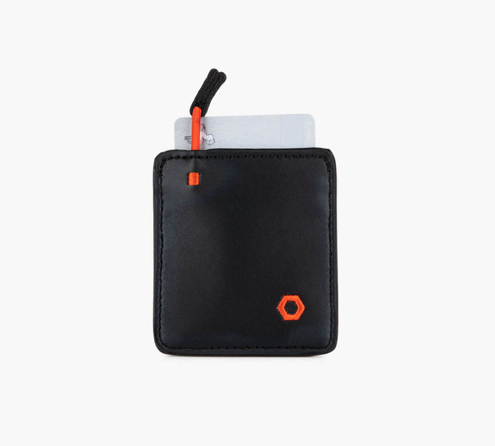Slim black card wallet with orange hexagon logo, white card partially visible and red pull tab
