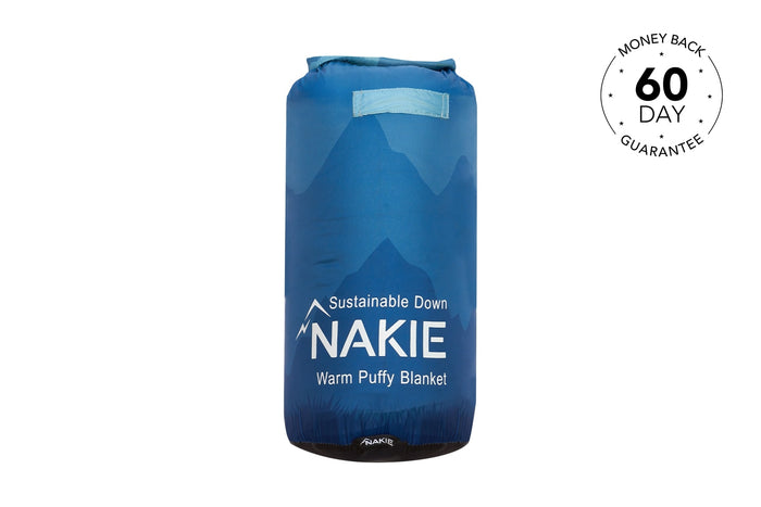 Blue puffy blanket with mountain graphic and carry handles, compressed into stuff sack form