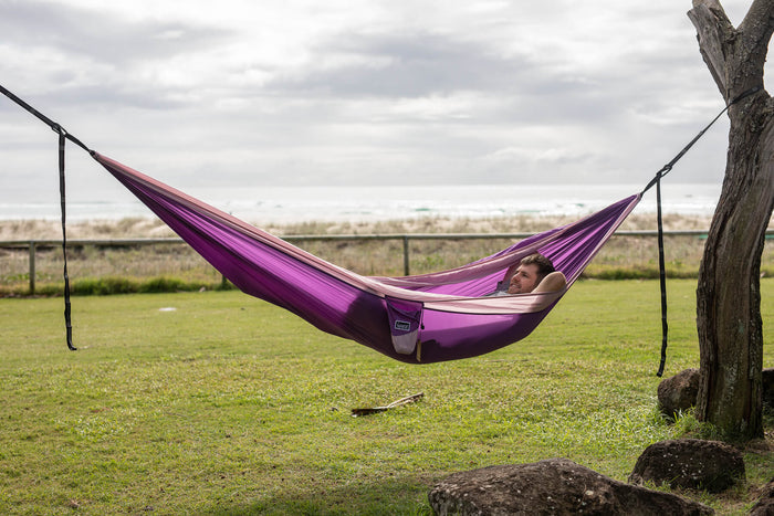 A calming image of a purple Nakie hammock elegantly stretched between two trees