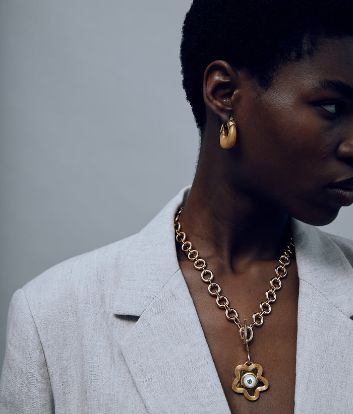 Model wears grey blazer with Mood Necklace in Gold,Porto Pendant in Poppy Pearl, and Organic Hoops in Mocha.