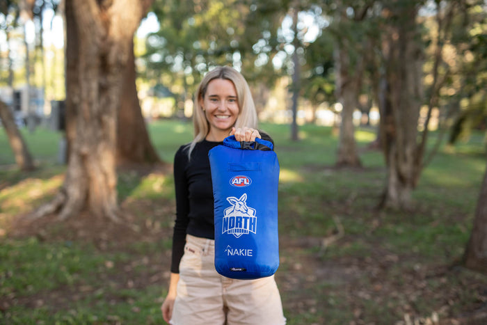 Blue North Melbourne Kangaroos AFL puffy blanket with roll-top closure, displayed by model outdoors