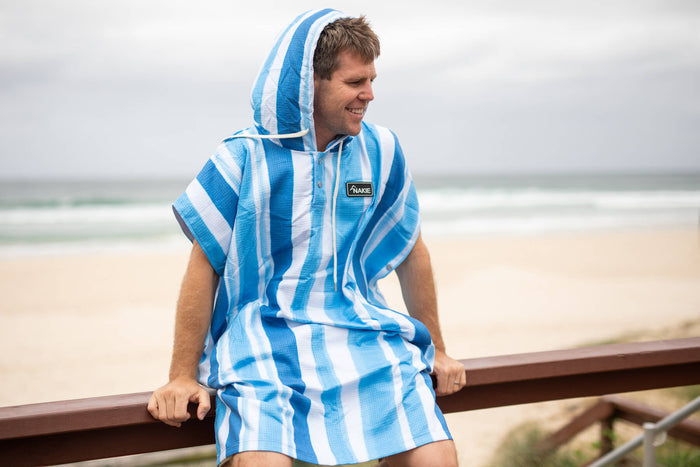 Blue and white striped hooded towel with short sleeves, worn over shoulder at beach