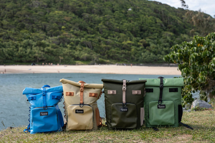 Spring green recycled cooler backpack with roll-top closure and shoulder straps, displayed outdoors by a beach