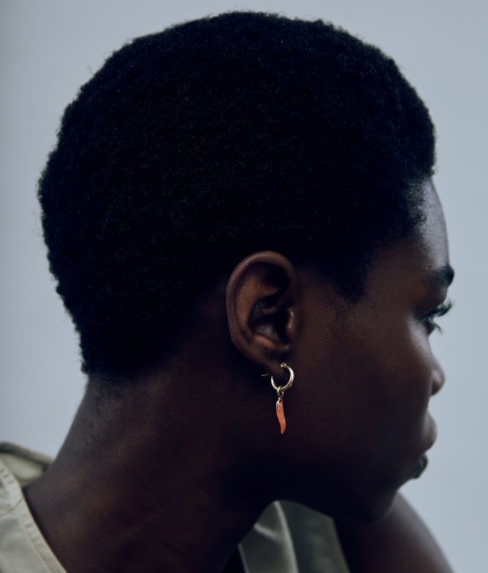 Model turns head and wears gold hoop with hanging Coral Horn charm.