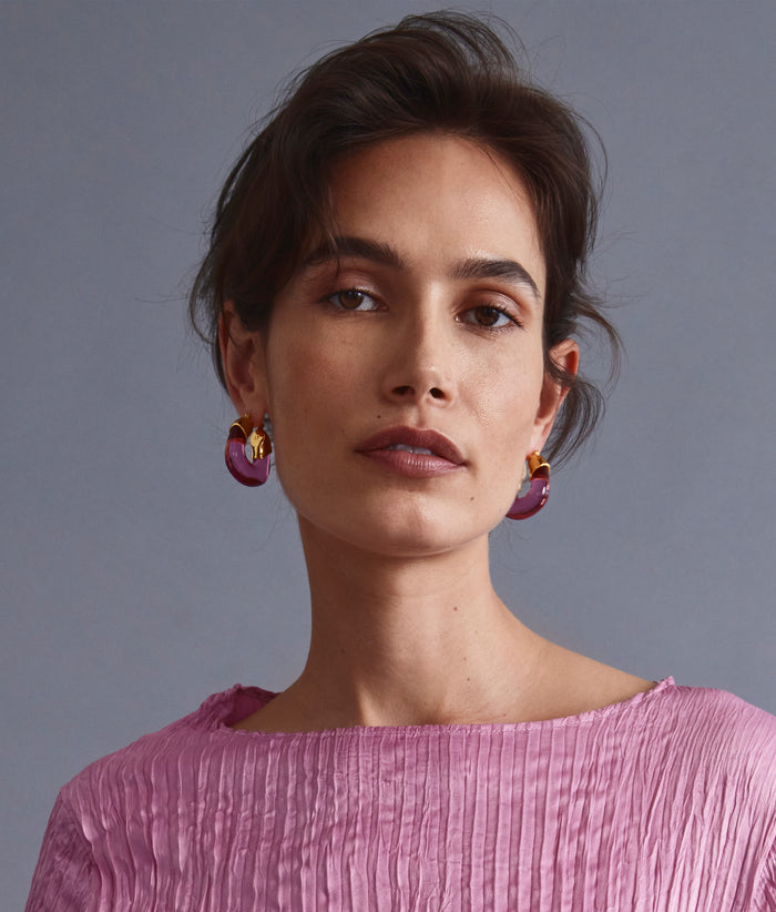 Model on grey background wearing Organic Hoops in Flamingo.