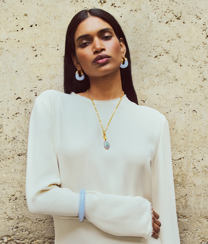 Model in cream dress wears Organic Hoops and Ridge Cuff in Blue Lace with Yucca Pendant Necklace