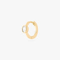 Gold huggie earring with a clear gemstone on a white background