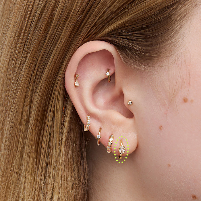 Close-up of an ear with multiple gold and diamond earrings.