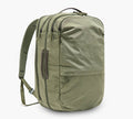 Three-quarter view of Pakt One Travel Backpack in cypress showing three zip compartments, side carry handle, and padded shoulder straps on white background