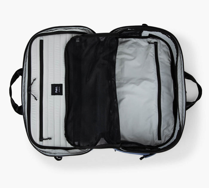 Overhead view of Pakt One Travel Backpack+ open showing dual compartments, mesh divider, zippered pockets, gray lining