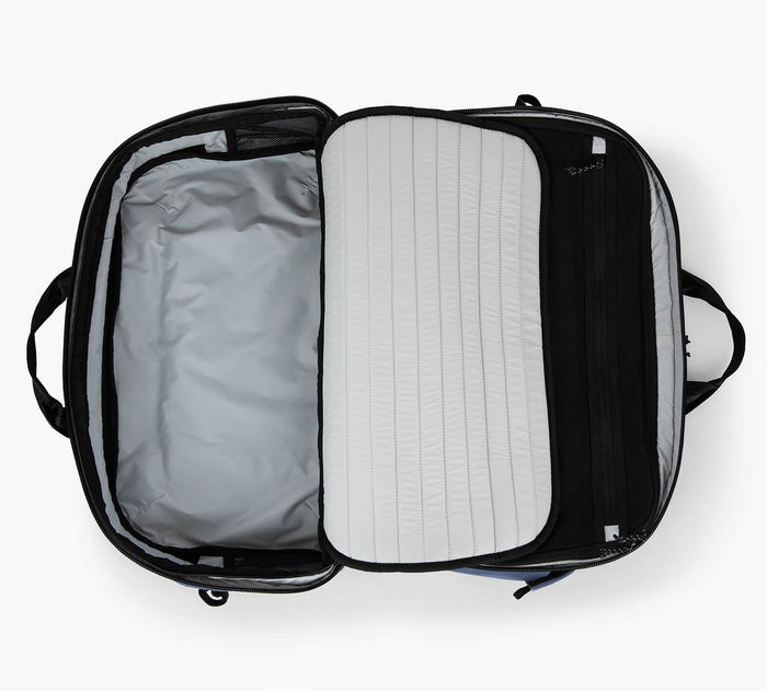Open carry-on suitcase viewed from above, empty main compartment and zippered divider with removable lined packing pad.