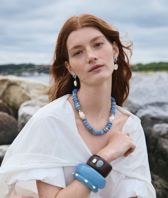 Model in Lanna Cuff Bracelet in Ridge Cuff in Glacier and Pearl, Umi Necklace, and Papaya Earrings in Pearl, and more.