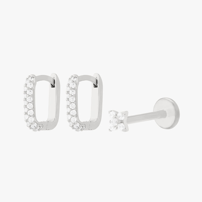 A silver earscape set featuring a pair of square pave huggies and a pave x flatback with clear stones