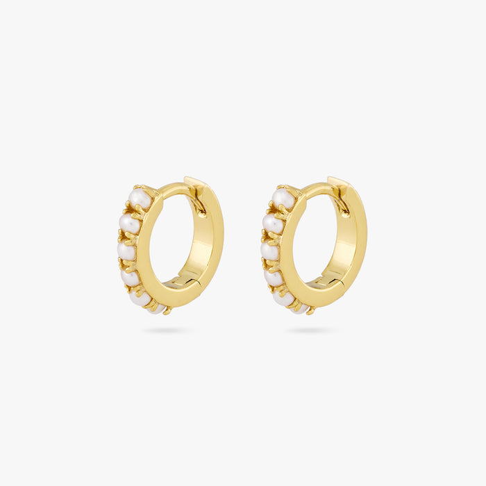 This is a pair of small gold huggies that have small pearls lining the front of them [pair] color:null|gold