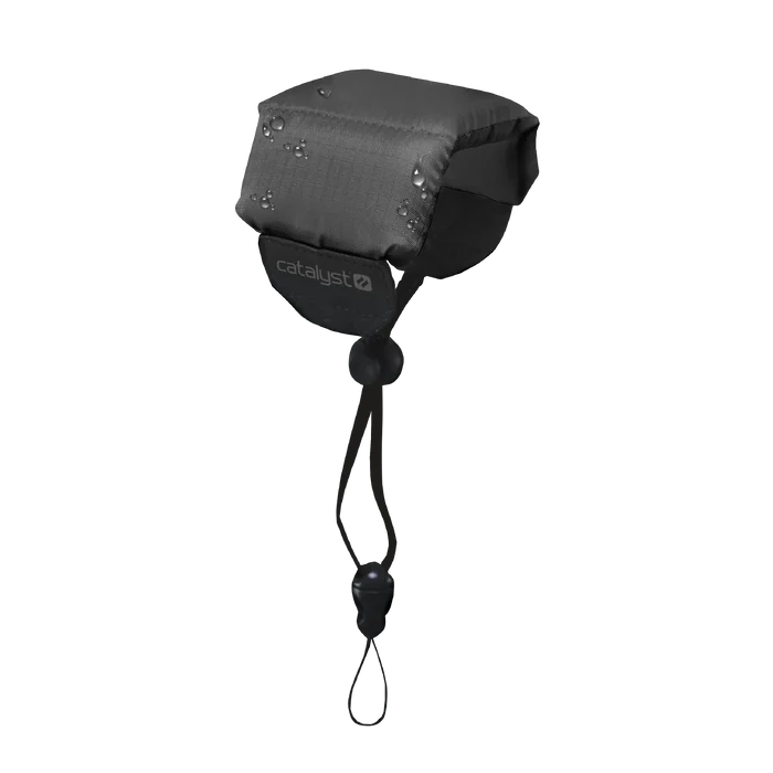 A Stealth Black Floating Lanyard by Catalyst Case US, featuring padding, a drawstring with toggle and clasp for secure attachment, sits against a plain background. The front displays the white "catalyst" logo. Water droplets are visible on the surface.