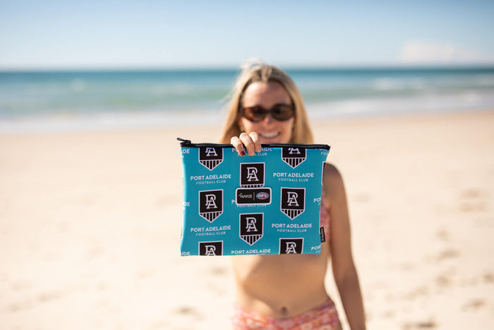 Turquoise Port Adelaide Football Club recycled beach towel with repeated black PA shield logos, displayed at the beach.