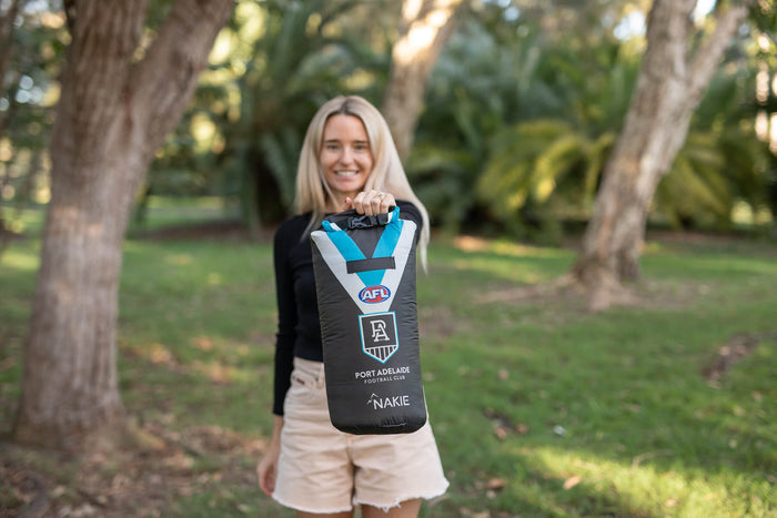 Port Adelaide Power AFL sustainable down puffy blanket in black with blue and white stripes, displayed outdoors
