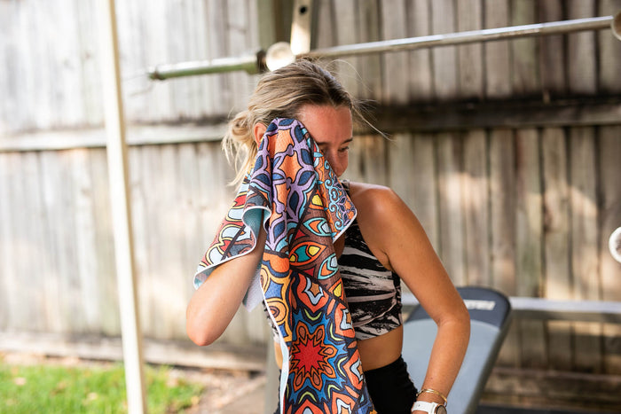 Recycled gym towel with vibrant multicolour geometric and abstract print, held by woman in athletic wear