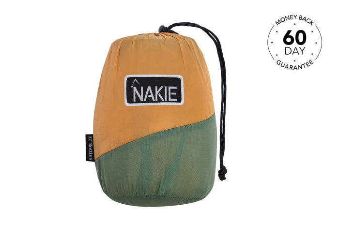 Tan and sage two-tone stuffed sleeping bag with black NAKIE logo patch and drawstring closure.