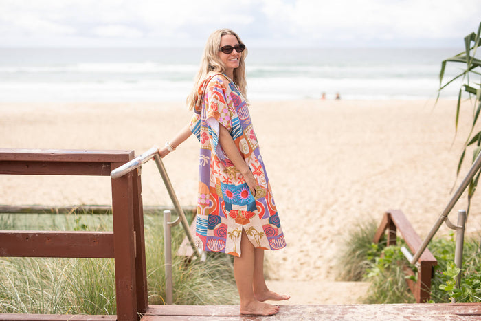 Hooded towel in bright multi-color retro print, worn as a beach cover-up at the shore.