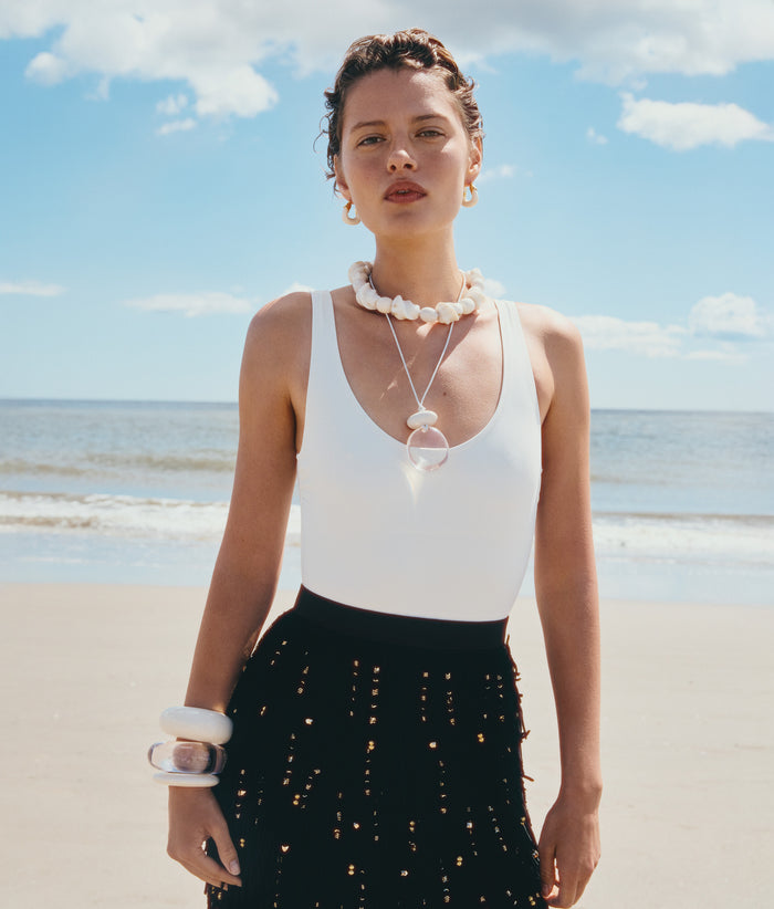 Model on beach wears white and black outfit with Salamanca and Lune Cord Necklaces, Ridge and Arc Cuffs