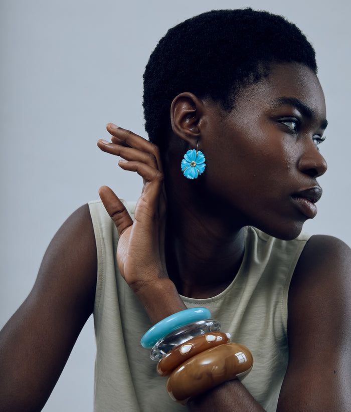 Model on grey background wearing Ridge Cuff in Marbled Aquamarine paired with ridge cuffs, arc cuff, new bloom earrings