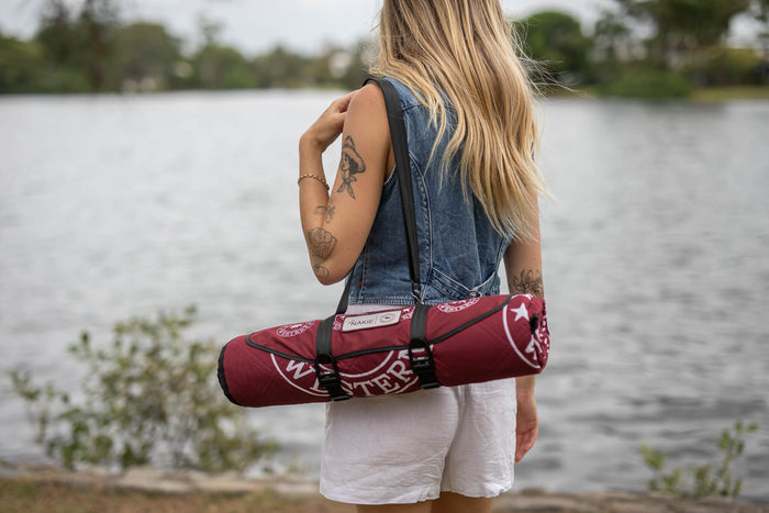 Burgundy recycled picnic blanket with white graphic print, rolled and carried over shoulder with black straps