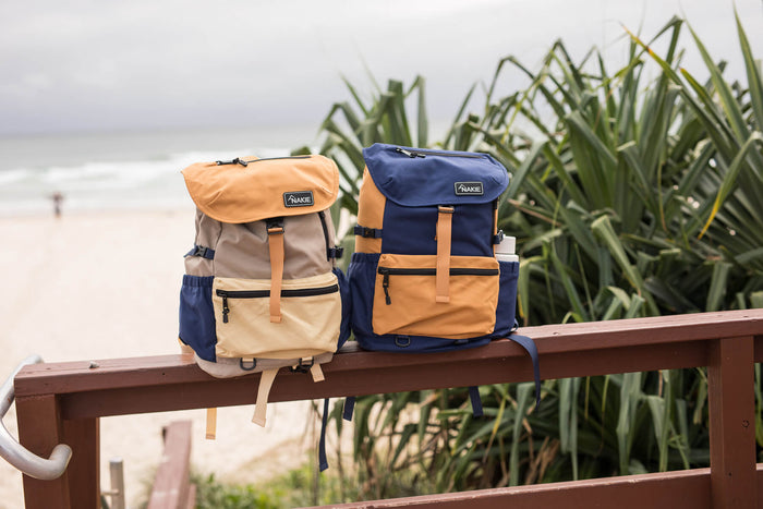 Two recycled travel backpacks in navy and tan colorblock design with tan straps