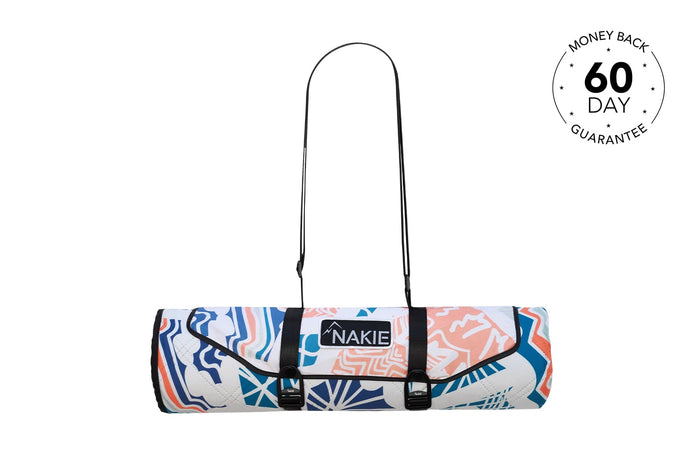 Rolled picnic blanket in blue, coral and white abstract print with black shoulder straps and Nakie logo patch