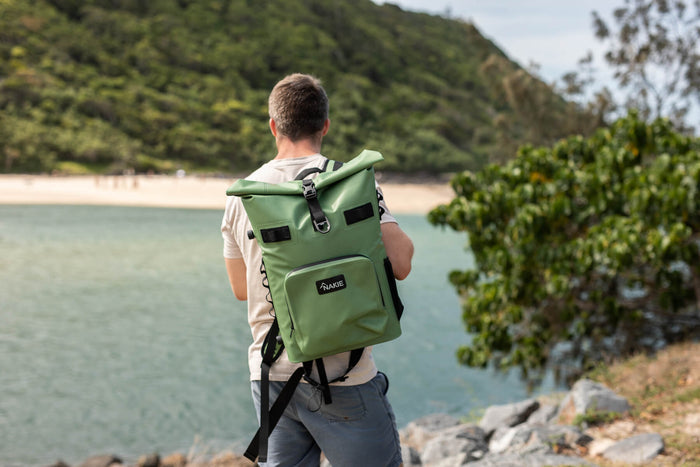 Spring green recycled cooler backpack worn by person at beach, roll-top closure with black straps