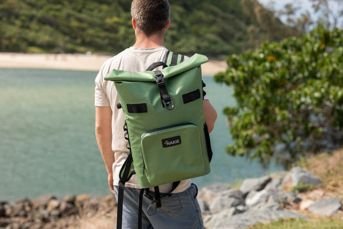Spring green recycled cooler backpack with black straps and front pocket, worn by person at beach