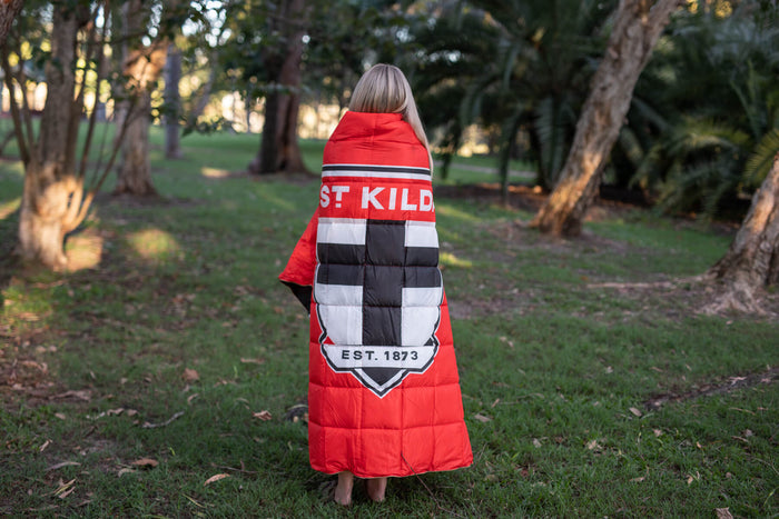Red St Kilda Saints puffy blanket with black and white block crest design, worn as a cape outdoors