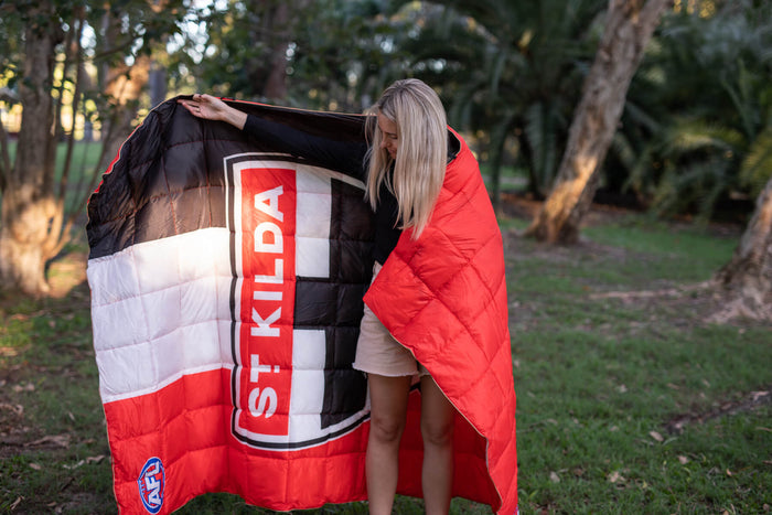 St Kilda Saints red, white and black quilted puffy blanket displayed outdoors, showing logo and text detail
