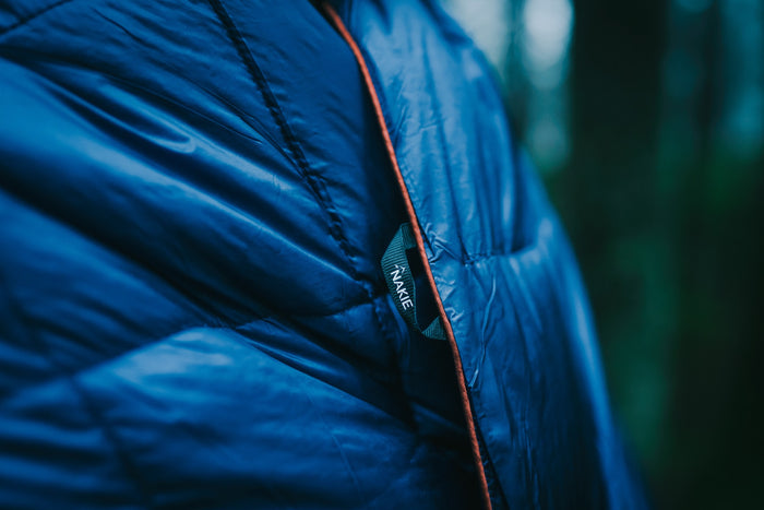 Blue puffy blanket with red zipper detail and brand label visible, close-up side view